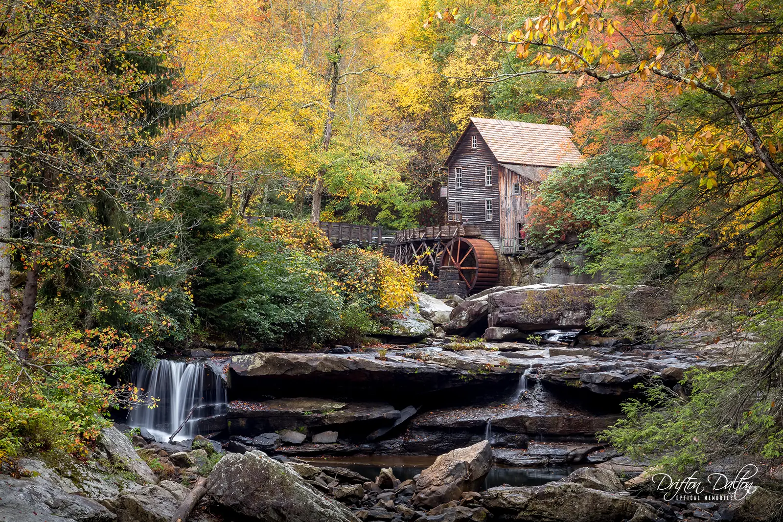 Historic grist mill surrounded by vivid autumn foliage and cascading water