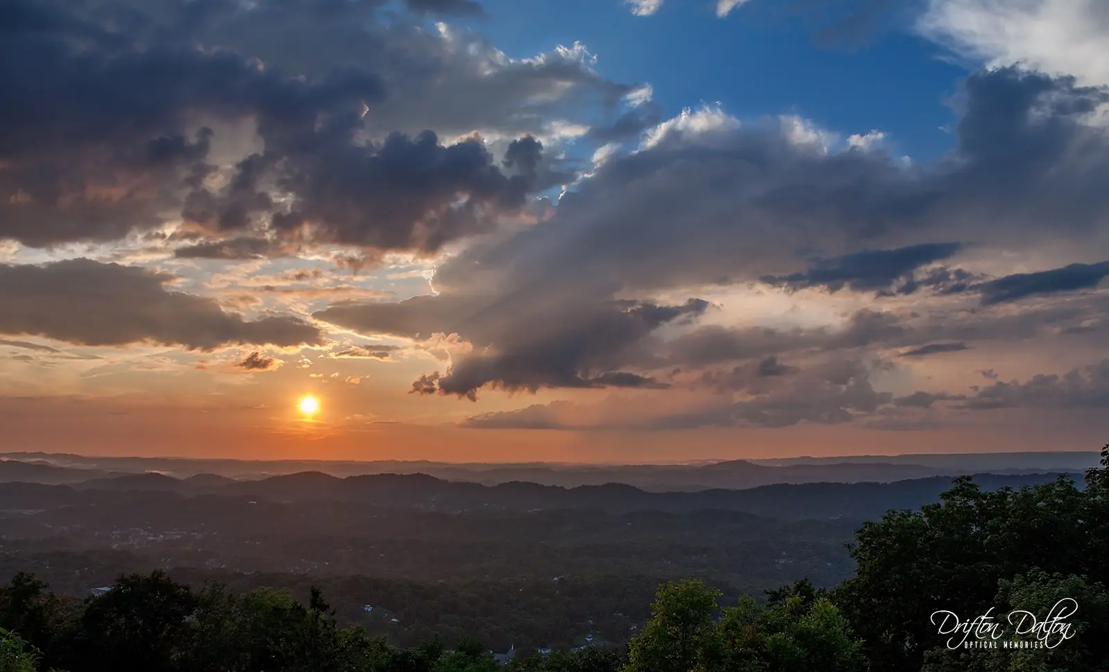 Sunlight breaking through storm clouds above layers of mountain ridges