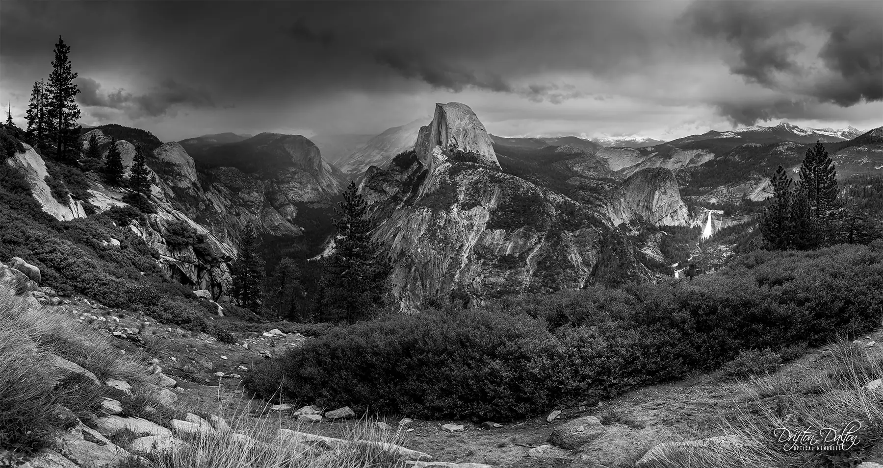 Black-and-white view from Glacier Point across Yosemite Valley toward Half Dome beneath storm clouds