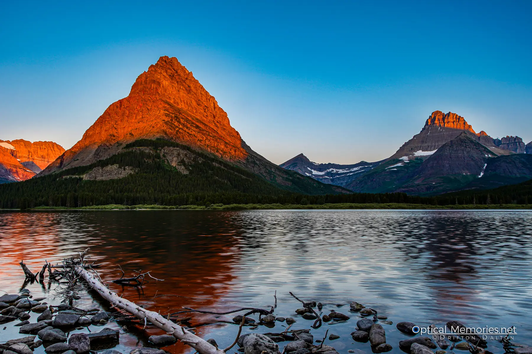 Golden morning light illuminating mountain peaks above Swiftcurrent Lake