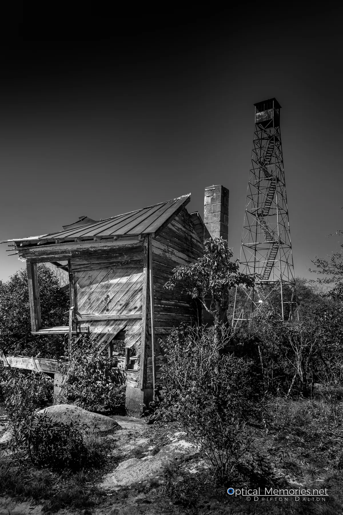 Abandoned wooden shelter and old fire tower rendered in black and white