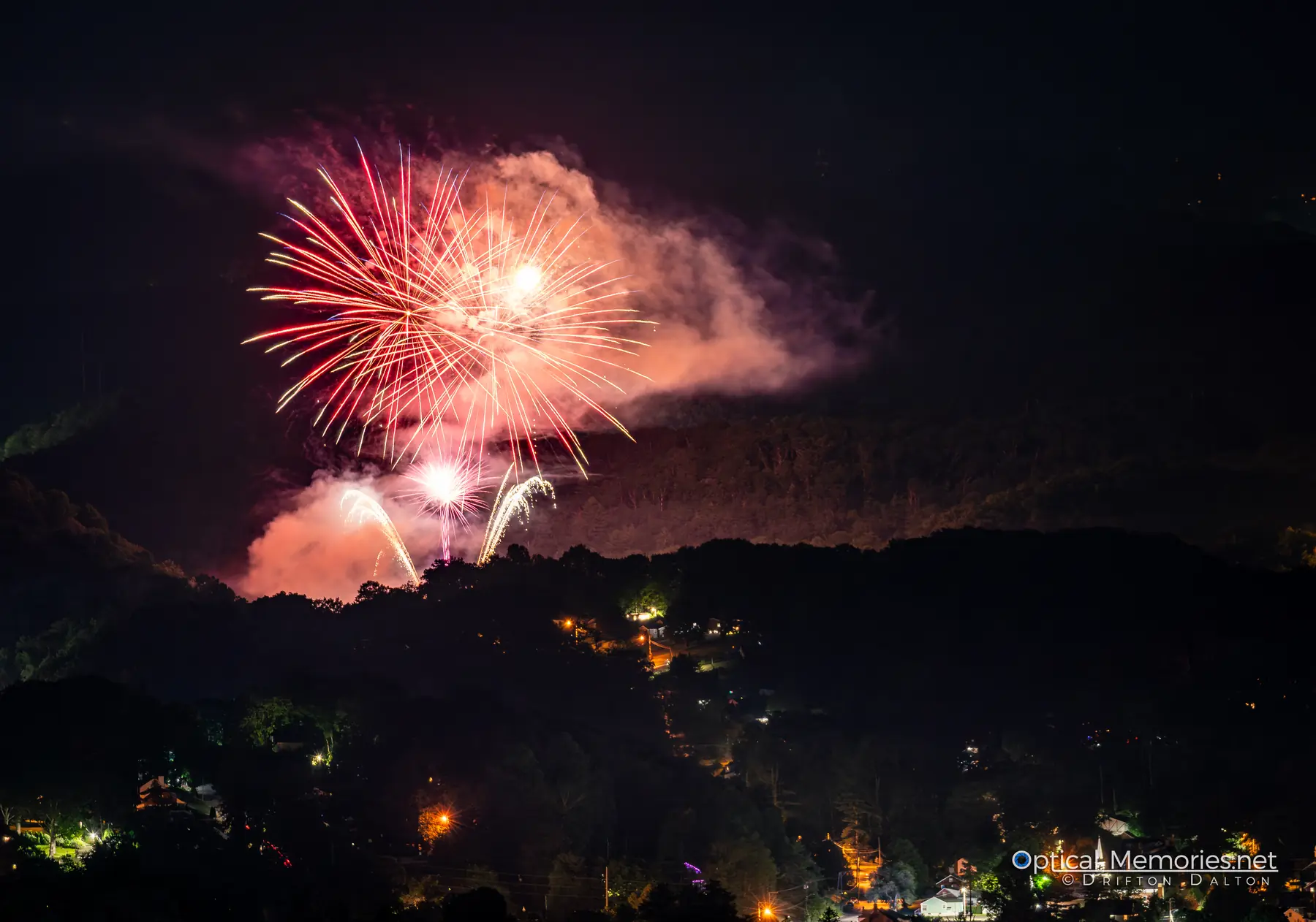 Fireworks glowing through smoke above Bluefield at night