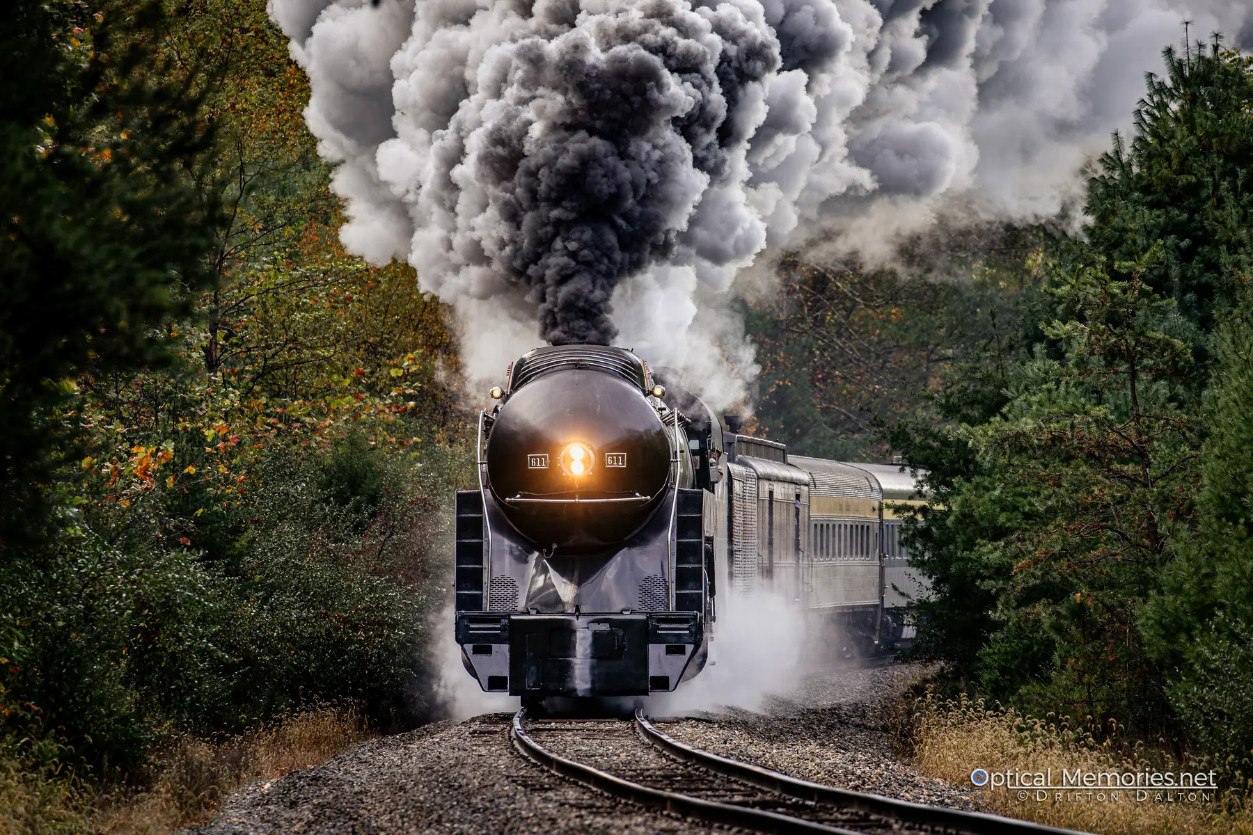 Norfolk and Western 611 charging through a curve beneath a towering plume of smoke